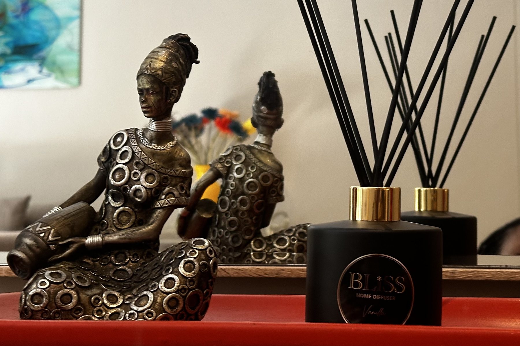 Bliss Home Diffuser in black and gold beside a South African figurine